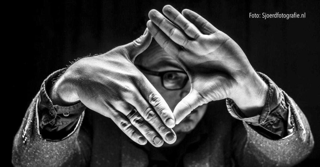 Mindhacker spreker op podium demonstreert mentale illusies en inspireert publiek door innovatieve psychologische technieken